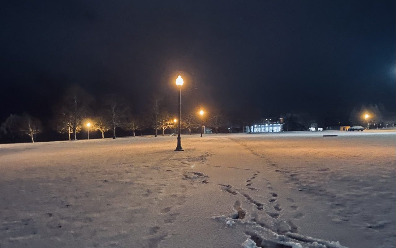 An evening scene of snow on a campus walkway.