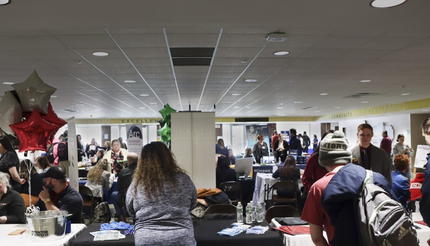 Wide shot of people at tables at the career fair