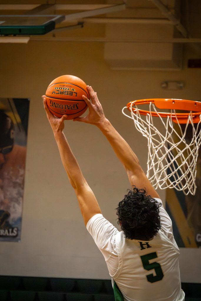 Basketball Player Grabbing Ball Near Hoop