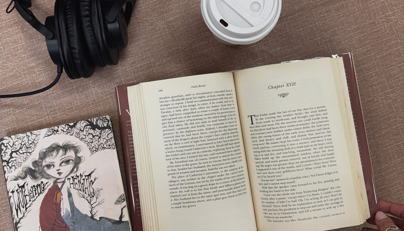 Book on table with headphones and disposable coffee cup