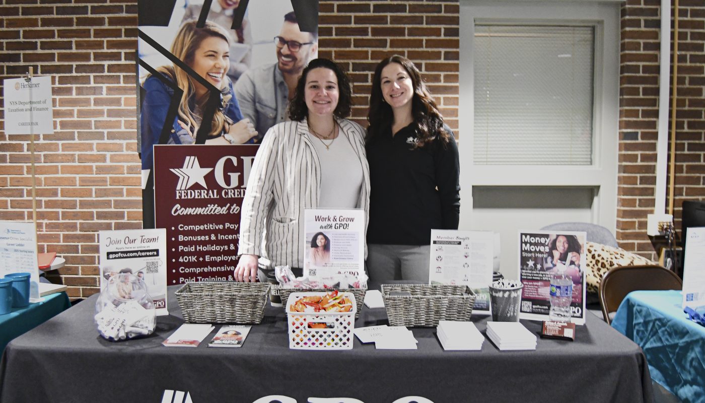Two women stand behind GPO table