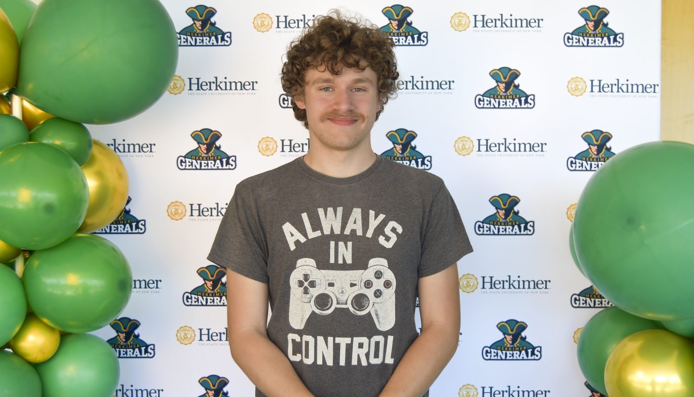 A student poses will balloons at Grad Fair