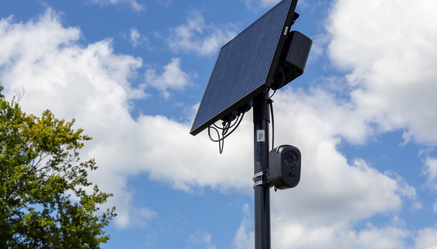 A Flock Camera against a blue sky with clouds