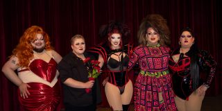 Group photo of drag show performers on stage